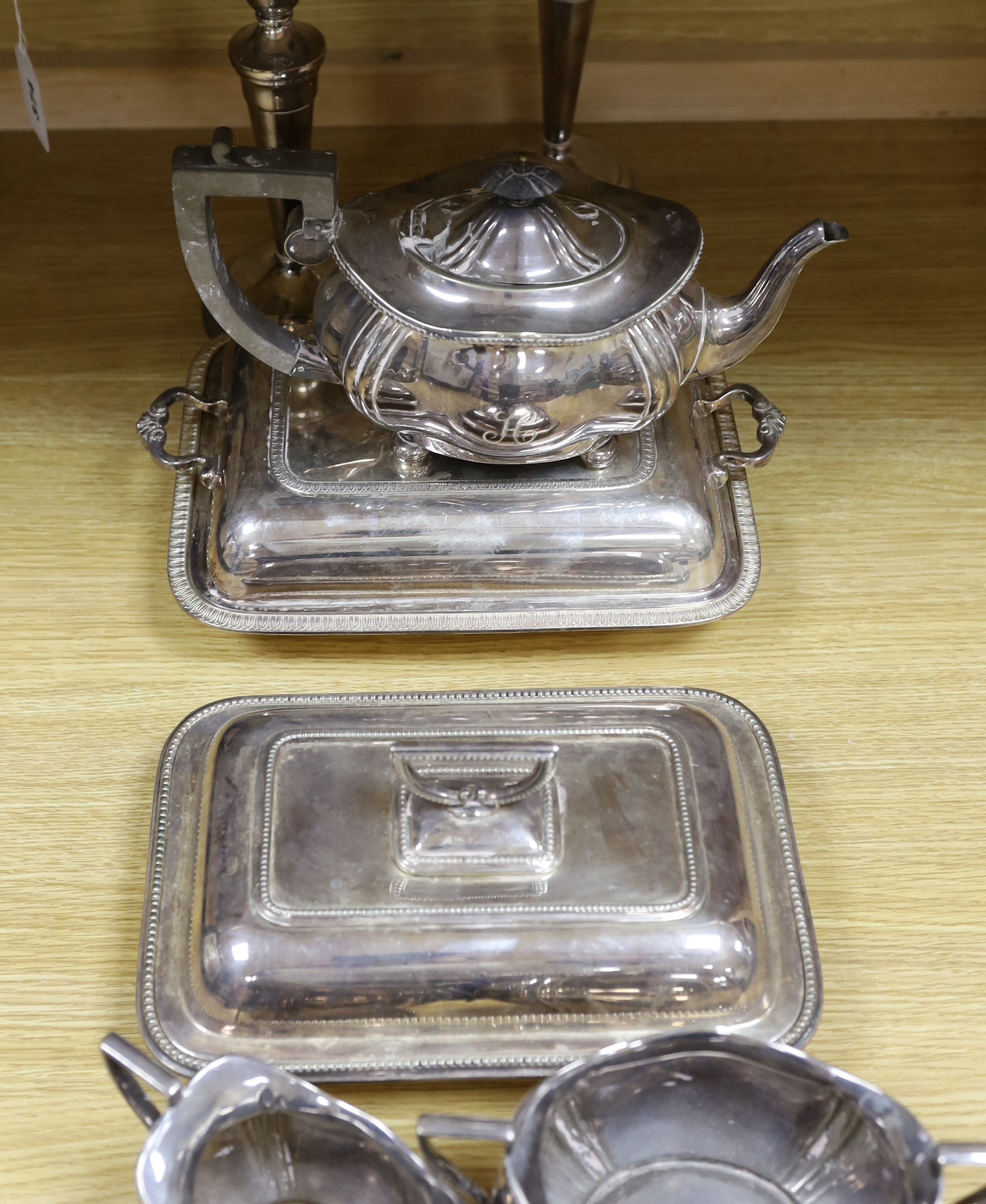 A group of silver plated items including a pair of three branched candlesticks, teapot, milk jug and sugar bowl, the largest 36cm high